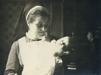 826203 Portret van wijkkraamzuster Jo Paap, werkend in een 'kraamwijk' te Utrecht, met een baby op haar arm